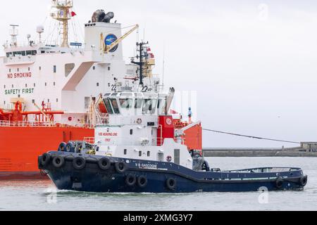 Le Havre, Frankreich - Blick auf den Hafenschlepper VB GASCOGNE kreuzt vor einem Öltanker im Hafen von Le Havre mit grauem Himmel. Stockfoto