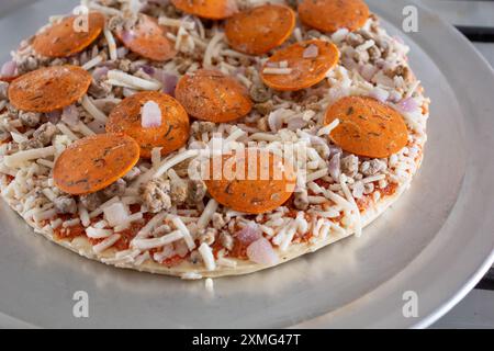 Eine Nahaufnahme der Beläge einer milchfreien und glutenfreien Tiefkühlpizza, die auf einem Herd liegt. Stockfoto