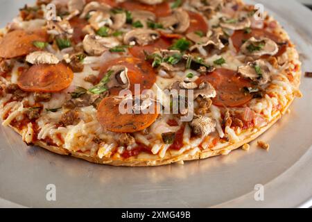 Eine Nahaufnahme der Beläge einer milchfreien und glutenfreien Tiefkühlpizza, die auf einem Herd liegt. Stockfoto