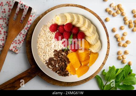 Köstliche und gesunde Schüssel mit Orange, Schokolade, Himbeeren und Bananenhafer. Stockfoto