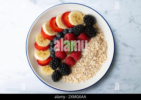 Köstliche und gesunde Schüssel Haferflocken mit roten Früchten, Himbeeren, Heidelbeeren, Erdbeeren und Banane. Stockfoto