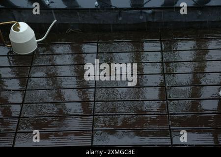 Wasserkanne auf dem nassen Balkon bei Regen Stockfoto