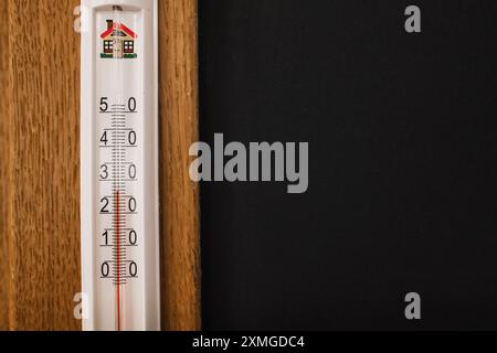 Innenthermometer an der Holzwand mit schwarzem Textfeld Stockfoto