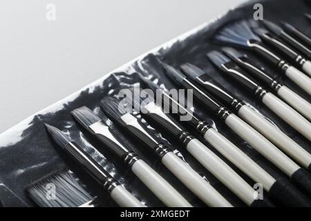 Pinsel, Palettenmesser in einem Federmäppchen auf weißem Leinenhintergrund. Nahaufnahme Stockfoto