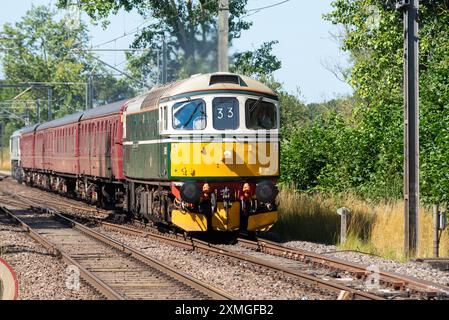 Ingatestone, Essex, Großbritannien. Juli 2024. Der Organisator UK Railtours betreibt einen klassischen dieselgeschleppten Personenzug vom Bahnhof London Fenchurch Street in die Küstenstadt Clacton-on-Sea in Essex, zunächst mit einer Lokomotive der British Rail Class 33 Nummer D6515 aus den 1960er Jahren bis nach Harwich. Eine Lokomotive der Baureihe 66 bringt den Zug nach Clacton und die Rückfahrt nach London. 98 dieselelektrische Lokomotiven der Baureihe 33 wurden zwischen 1960 und 1962 für die südliche Region der British Railways gebaut, die letzte wurde Mitte der 1990er Jahre ausgemustert Stockfoto