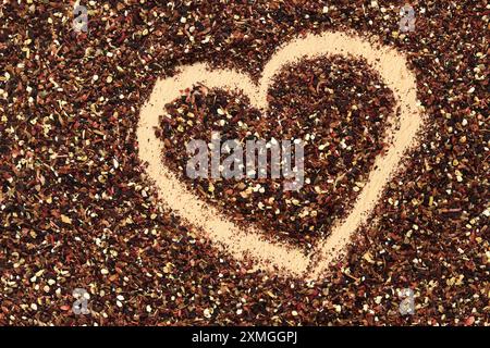Herz auf verschüttetem Früchtetee gezeichnet, Textur. Blick von oben auf Tee aus Apfel, Zimt, Zitronenschale, Hibiskusblüten, Süßholzwurzel und Nelken. Tee gratis Stockfoto