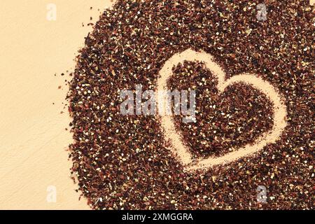 Herz auf verschüttetem Früchtetee gezeichnet, Textur. Blick von oben auf Tee aus Apfel, Zimt, Zitronenschale, Hibiskusblüten, Süßholzwurzel und Nelken. Tee gratis Stockfoto