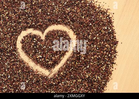 Herz auf verschüttetem Früchtetee gezeichnet, Textur. Blick von oben auf Tee aus Apfel, Zimt, Zitronenschale, Hibiskusblüten, Süßholzwurzel und Nelken. Tee gratis Stockfoto