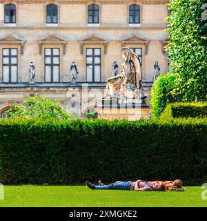 FRANKREICH. PARIS (75) 1. BEZIRK. LOUVRE MUSEUM. KARUSSELLGÄRTEN. EIN PAAR, DAS AUF EINEM RASEN LIEGT Stockfoto