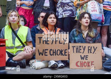 London, Großbritannien. Juli 2024. Die Demonstranten halten Plakate mit dem Motto "Sie fliegen, wir ersticken". Aktivisten versammelten sich vor dem Verkehrsministerium, um gegen Pläne für eine Erweiterung des Londoner City Airport zu protestieren, die zu erhöhten Emissionen und Umweltverschmutzung führen würde. Quelle: SOPA Images Limited/Alamy Live News Stockfoto