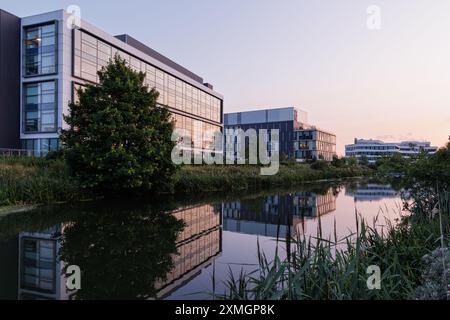 Northamptonshire, Großbritannien - Juli 2024: Gebäude des Riverside Campus der University of Northampton spiegeln sich bei Sonnenuntergang im Fluss Nene. Stockfoto