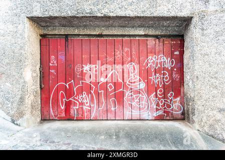 Salvador, Bahia, Brasilien - 27. Juli 2024: Hölzerne Garagentür eines alten Hauses in Pelourinho, bedeckt mit Graffiti. Stadt Salvador, Bahia. Stockfoto