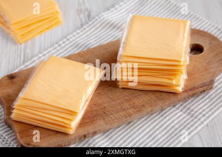Gelber Cheddar American Cheese Stapelscheiben auf Holzbrett, Seitenansicht. Stockfoto