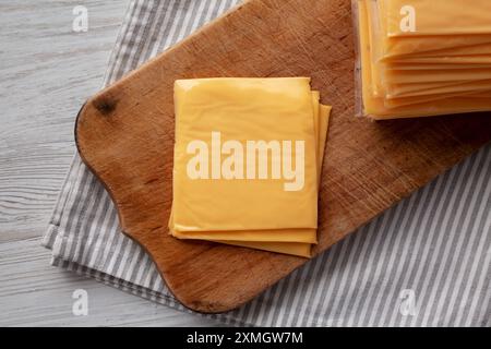Gelber Cheddar American Cheese Stapelte Scheiben auf Holzbrett, Draufsicht. Stockfoto
