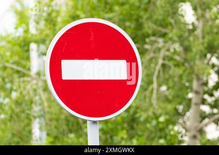 Nahaufnahme eines roten Verkehrsschilds mit grünem Laubhintergrund, das auf eingeschränkten Zugang hinweist. Stockfoto