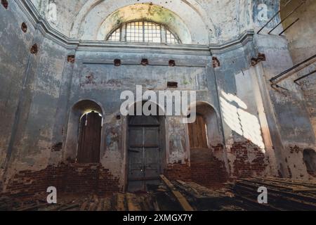 Innenansicht einer verlassenen Kirche mit Schwerpunkt auf der sich verschlechternden Kuppel mit abblätternder Farbe und freiliegenden Ziegeln, die das Alte und die Weite des Gebäudes einfangen Stockfoto