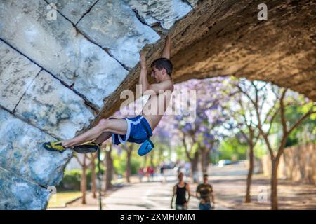 Junge Kletterer üben Freiklettern unter der berühmten Triana-Brücke in Sevilla, Andalusien, Spanien. Stärke und Entschlossenheit zeigen. Stockfoto