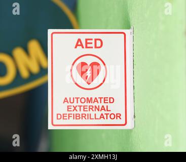 Elektrodefibrillator-Logo auf einem Schild in einer städtischen Umgebung, das auf das Vorhandensein eines AED-Geräts in der Nähe hinweist; Stockfoto