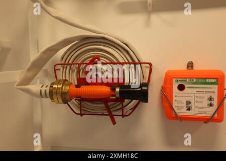 Feuerwehrausrüstung, Feuerlöscher, Axt und Feuerleitung in roter Box. Löschkonzept. Stockfoto