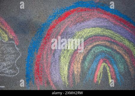 Kreidezeichnung. Ein Regenbogen auf dem Asphalt. Aktivitäten für Kinder. Farbige Kreide im Hintergrund. Zurück zur Schule. Stockfoto