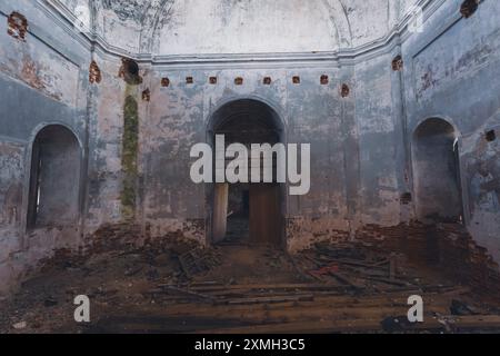 Das Innere einer verlassenen Kirche mit verfallenen Mauern, kaputten Fenstern und Schutt auf dem Boden. Die Bögen und gewölbten Decken geben einen Sinn Stockfoto