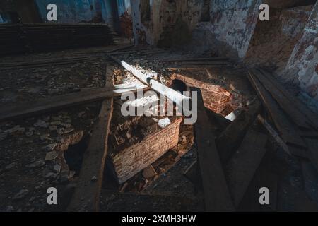 Ein Innenblick auf eine verlassene Kirche mit einem zusammengebrochenen Boden mit Holzbalken und Ziegeln, die verstreut sind. Der Verfall und die Verschlechterung im Inneren Stockfoto