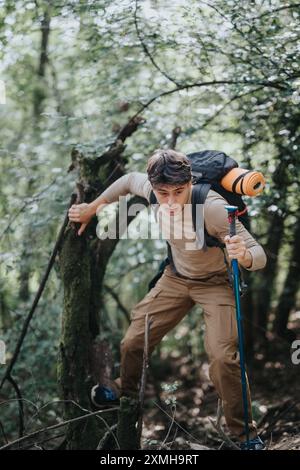 Junger Mann, der durch dichten Wald wandert, mit Rucksack und Trekkingstöcken durch zerklüftetes Gelände navigiert Stockfoto