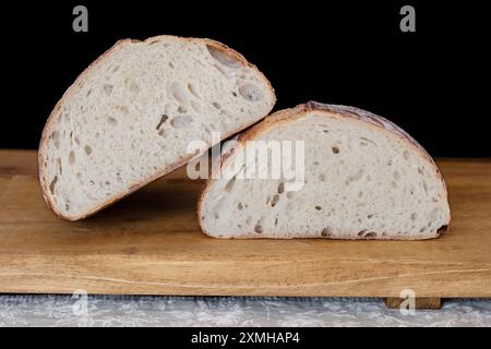 UK. Ein Stück frisch gebackenes, hausgemachtes Sauerteigbrot. Der Brotlaib wurde halbiert, um die für dieses Brot charakteristische offene Krume zu zeigen Stockfoto