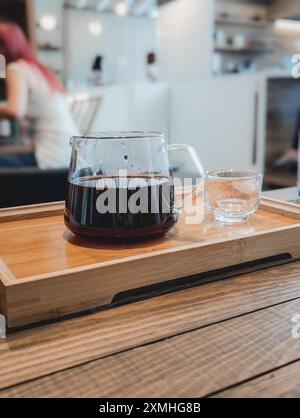 Kaffeespezialitäten in Glaskaraffe mit Tasse und Tablett im Café, Hongkong Stockfoto