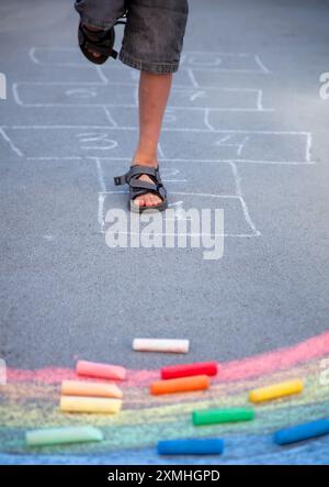 Hopscotch mit Kreide auf dem Bürgersteig gezeichnet. Kinderfüße. Auf Plätzen auf der Straße zu springen. Farbige Kreide Stockfoto