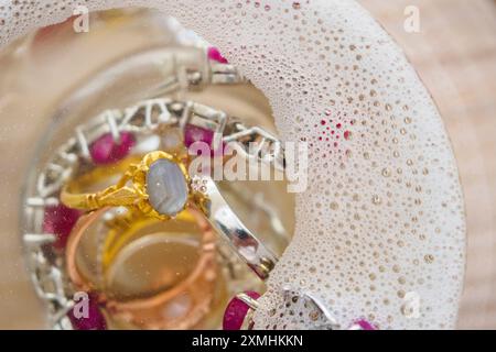 Reinigung Vintage Schmuck Diamant Ring und Armband in Glas auf Holztischhintergrund Stockfoto