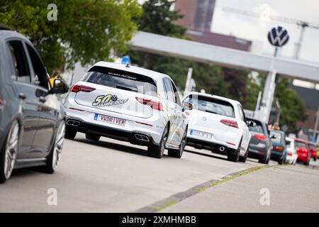 Wolfsburg, Deutschland. Juli 2024. Eine Autokolonne vom GTI Fanfest 2024 fährt durch ein Tor zum Volkswagen Werksgelände. Das traditionelle GTI Get-Together findet vom 26. Bis 28. Juli 2024 unter dem Motto „Coming Home – Reloaded“ statt. Quelle: Michael Matthey/dpa/Alamy Live News Stockfoto