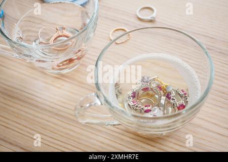 Reinigung Vintage Schmuck Diamant Ring und Armband in Glas auf Holztischhintergrund Stockfoto