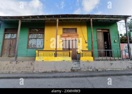 557 Grüne und gelbe Holzfassade, einstöckiges altes Kolonialhaus mit Eingangsveranda auf Holzsäulen, 33-35 Calle Maceo Street. Baracoa-Kuba. Stockfoto