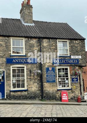 Ein Antiquitätengeschäft am berühmten Steilhang Hill in der historischen Altstadt von Lincoln, Großbritannien. Die Fassade zeigt ein Straßenschild für Steilhang Hill. Stockfoto