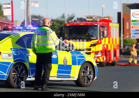 Ein Polizeibeamter stand neben seinem Fahrzeug, das bei einem Vorfall auf der Canal Road in Leeds, West Yorkshire, Großbritannien als Straßensperre benutzt wird Stockfoto