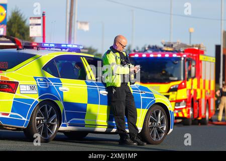 Ein Polizeibeamter stand neben seinem Fahrzeug, das bei einem Vorfall auf der Canal Road in Leeds, West Yorkshire, Großbritannien als Straßensperre benutzt wird Stockfoto