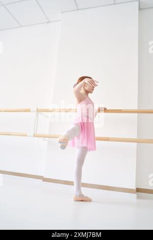 Ein junges Ballettmädchen beim Studiounterricht. Trainingsleistung. Stretching-Übungshaltung. Ballerina-Praxis-Balance-Technik. Klassische Eleganz Fitness. Tanzkostüm. Pinkfarbenes Kleid, Rock Stockfoto