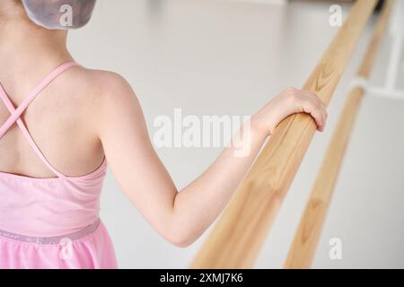 Ein junges Ballettmädchen beim Studiounterricht. Trainingsleistung. Stretching-Übungshaltung. Ballerina-Praxis-Balance-Technik. Klassische Eleganz Fitness. Tanzkostüm. Nahaufnahme. Pinkfarbenes Kleid, Rock Stockfoto