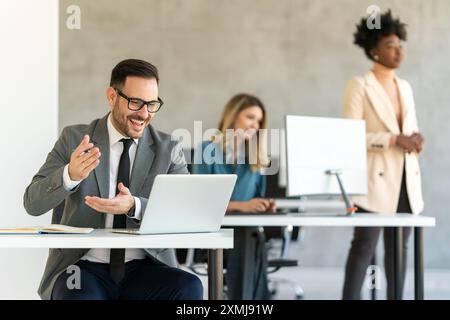 Geschäftsleute mit Kollegen im Büro überwachen Bestandsdaten auf dem Bildschirm und analysieren den Preisfluss Stockfoto