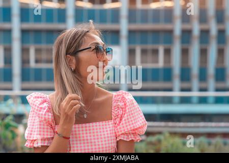 Asiatische Matrizenfrau in rosa Kleid und Sonnenbrille mit rosa Regenschirm, die spazieren geht, sitzend, eine lustige Zeit im Zentrum der Stadt hat Stockfoto