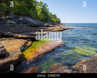 Sonnenlicht tanzt auf dem klaren Wasser, das über moosbedeckte Klippen am Lake Ontario im Robert G. Wehle State Park im Norden von New York, wo die Hor Stockfoto
