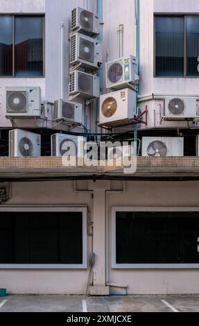 Viele Klimaanlagenfenster stapelten sich zufällig an der Fassade eines Gebäudes in Bangkok, Thailand. Stockfoto