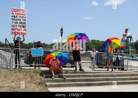 Harrisburg, Usa. Juli 2024. Mitglieder der Silent Witness Peacekeepers Alliance halten Regenbogenschirme, während sie während des 32. Pride Festivals der Central PA am 27. Juli 2024 in Harrisburg, Pennsylvania, vor Demonstranten stehen. Die Stille Zeugin bietet einen nicht-konfrontativen Puffer zwischen der LGBTQ-Community und den Demonstranten während LGBTQ-Veranstaltungen. (Foto: Paul Weaver/SIPA USA) Credit: SIPA USA/Alamy Live News Stockfoto