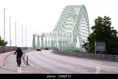 Cheshire, Großbritannien, 28. Juli 2024. Der Juli endet warm in der Gegend um Widnes Runcorn in Cheshire UK mit einer Temperatur von 25 °C. Ein Radfahrer und Autos auf der Silver Jubilee Bridge, die Widnes mit Runcorn verbindet. Quelle: Terry Waller/Alamy Live News Stockfoto