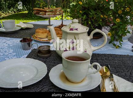 Traditioneller englischer Cream Tea mit Scones und Gurken-Sandwiches auf der Gartenterrasse Stockfoto