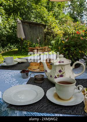 Traditioneller englischer Cream Tea mit Scones und Gurken-Sandwiches auf der Gartenterrasse Stockfoto