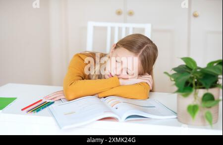 Teenager-Mädchen, Die Auf Offenem Lehrbuch Am White Table Schlafen Stockfoto