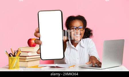 African American School Girl Bei Laptop Raising Hand, Gelber Hintergrund Stockfoto