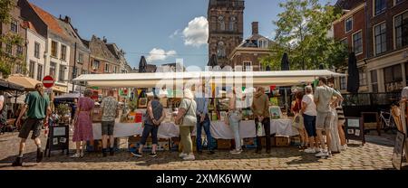 Straßenszene mit Menschen, die an einem sonnigen Tag auf dem örtlichen Buchmarkt in der Altstadt des Turms am Groenmarkt spazieren Stockfoto